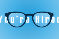 The words "you're hired" viewed through glasses. Everything outside the lens is blurry.